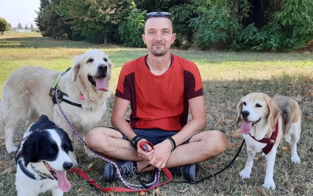 Dog trainer Francesco sitting on the grass with Diana the Beagle and two client dogs during a walk